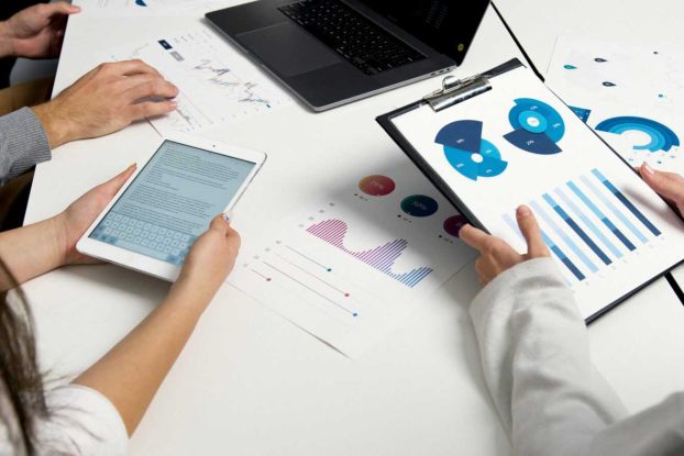 Team analyzing financial charts and digital reports during a business meeting.